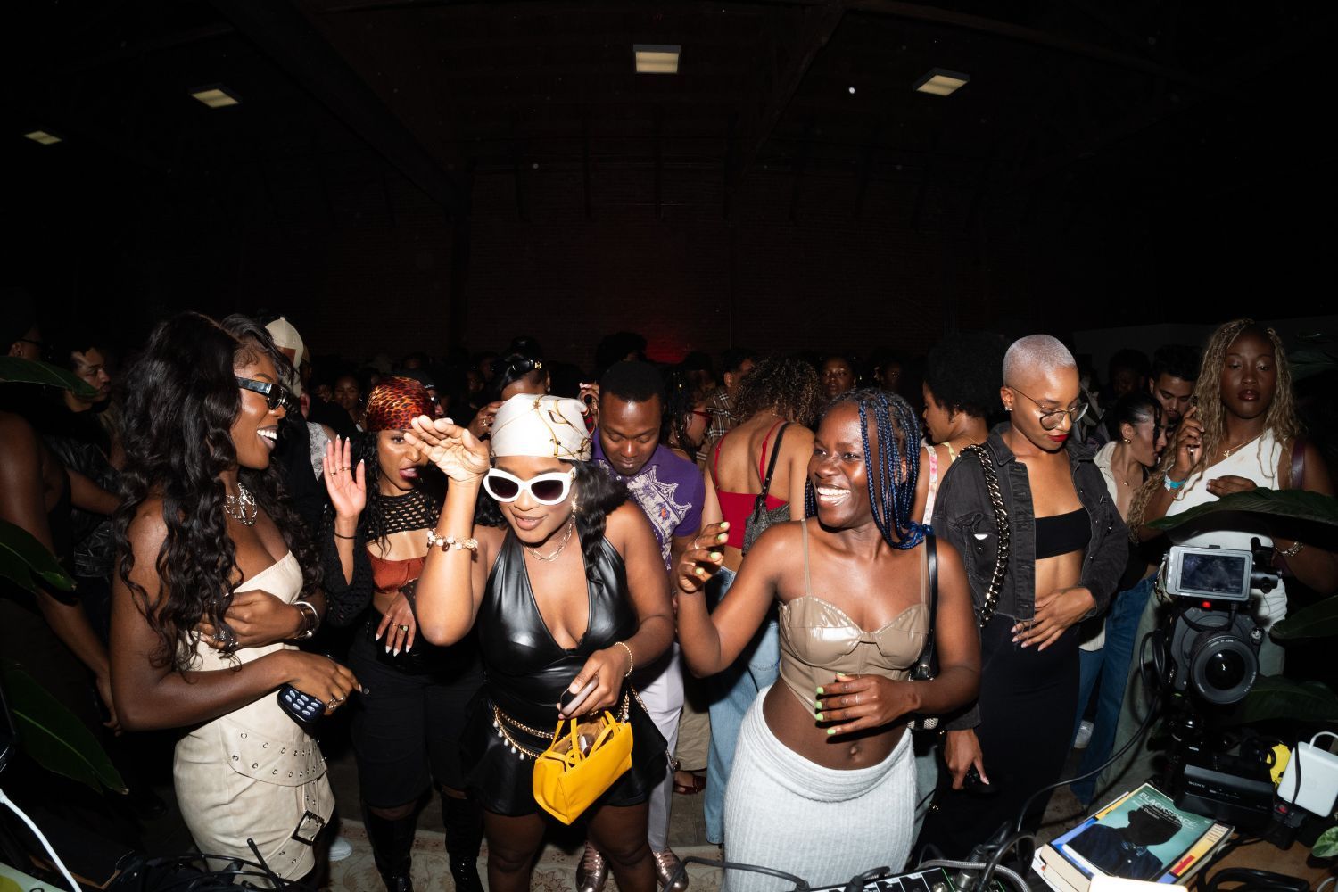 A group of stylish women laugh and dance in a lively crowd during the Motherland Sounds party