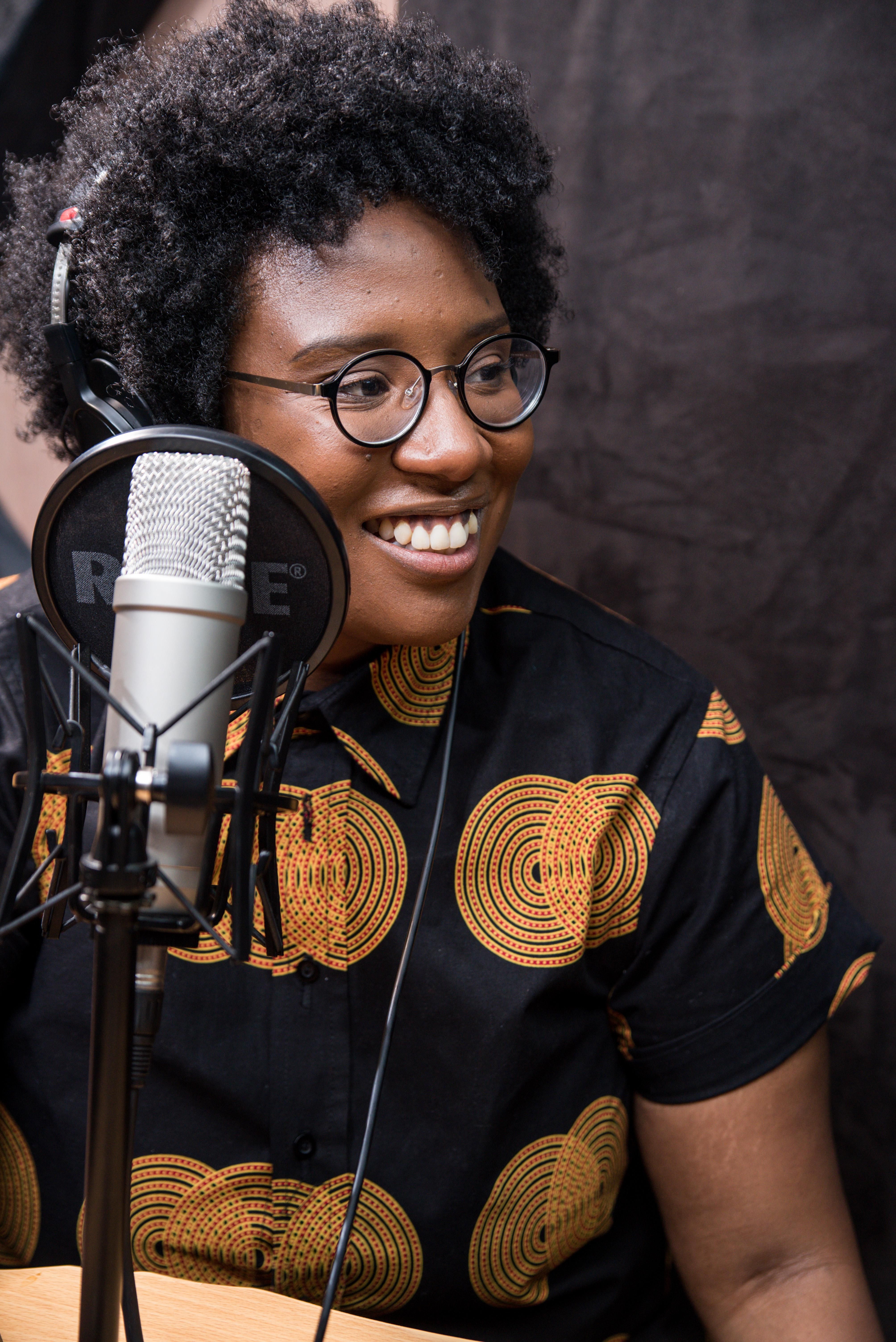 An image of Selly Thiam sitting at a podcasting microphone