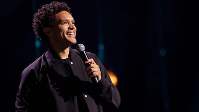 Trevor Noah in a black jacket with a microphone. 