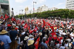A large crowd of protesters waving flags in Tunisian colors