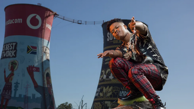 Nasty C posing on a rock to a backdrop of the Soweto skyline. 