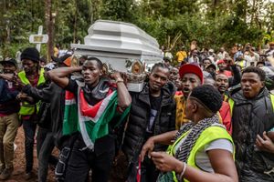Young Kenyans chant as they carry a white coffin on their shoulders, one of the young men in front draped in a Kenyan flag. 