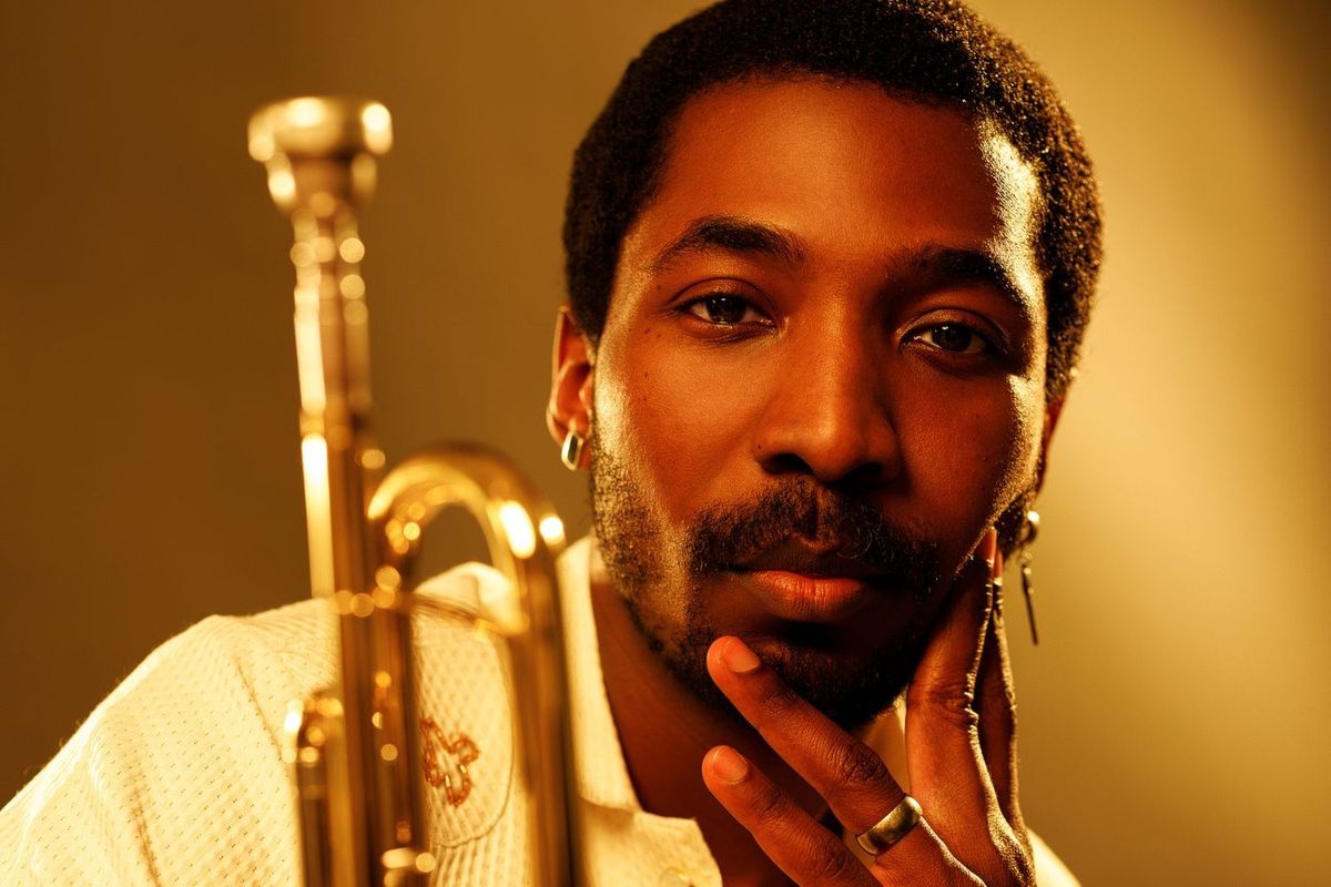 Mádé Kuti faces the camera, holding a saxophone and rocking matching gold jewelry