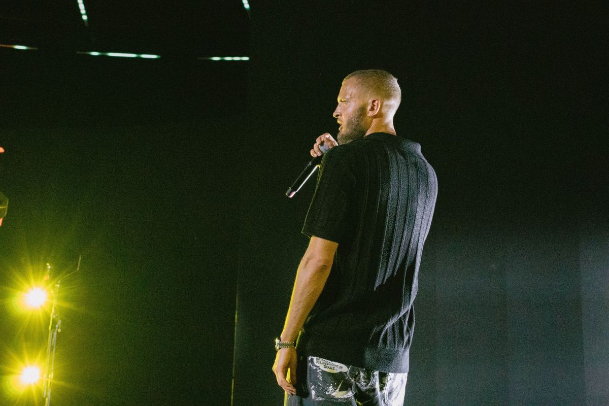 Marwan Moussa performing on stage, wearing a black t-shirt and trousers with cartoon prints.