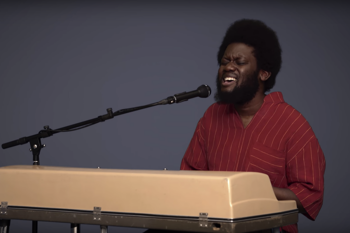 Michael Kiwanuka playing a keyboard and singing into a microphone 