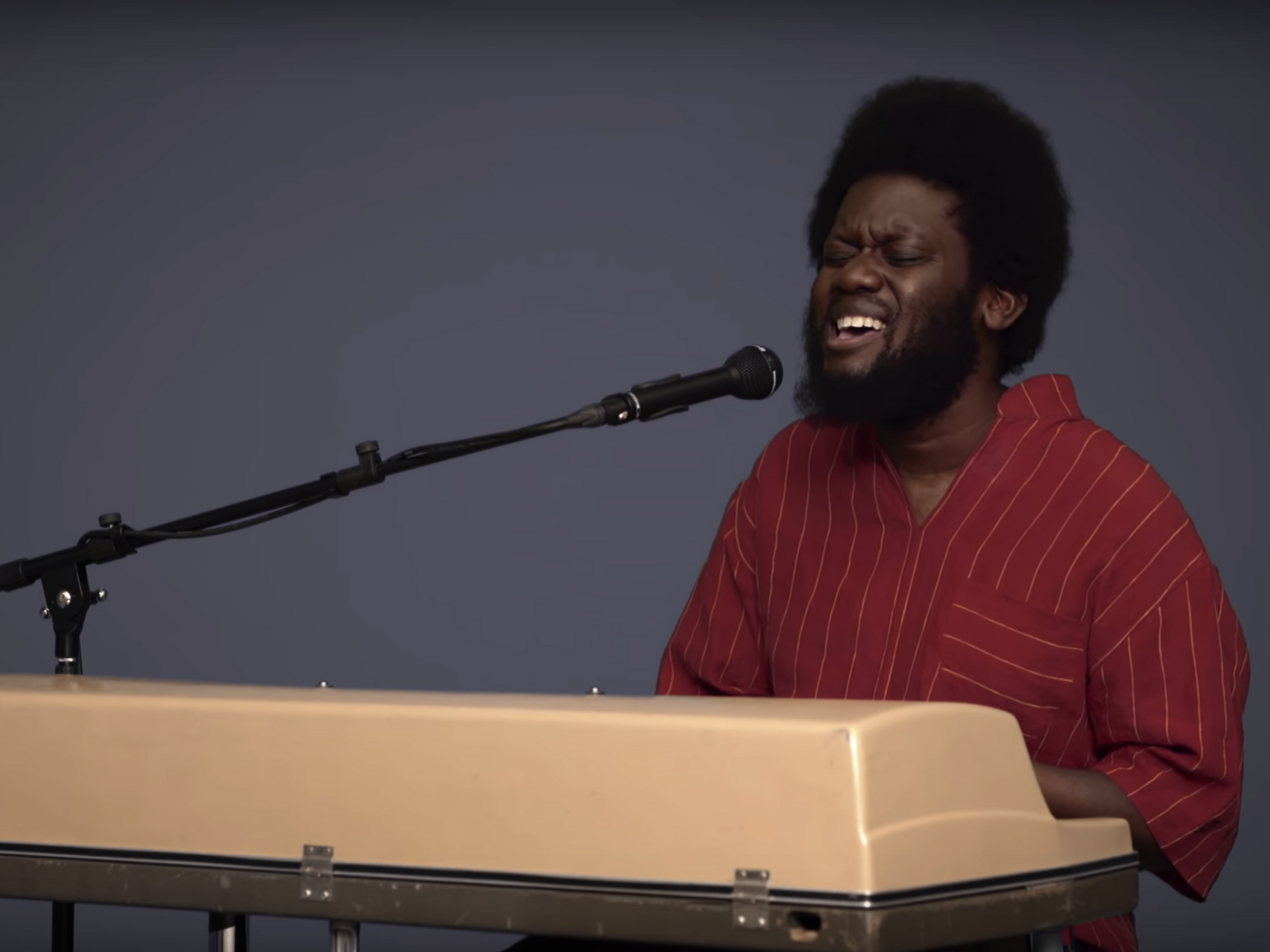 Michael Kiwanuka playing a keyboard and singing into a microphone 