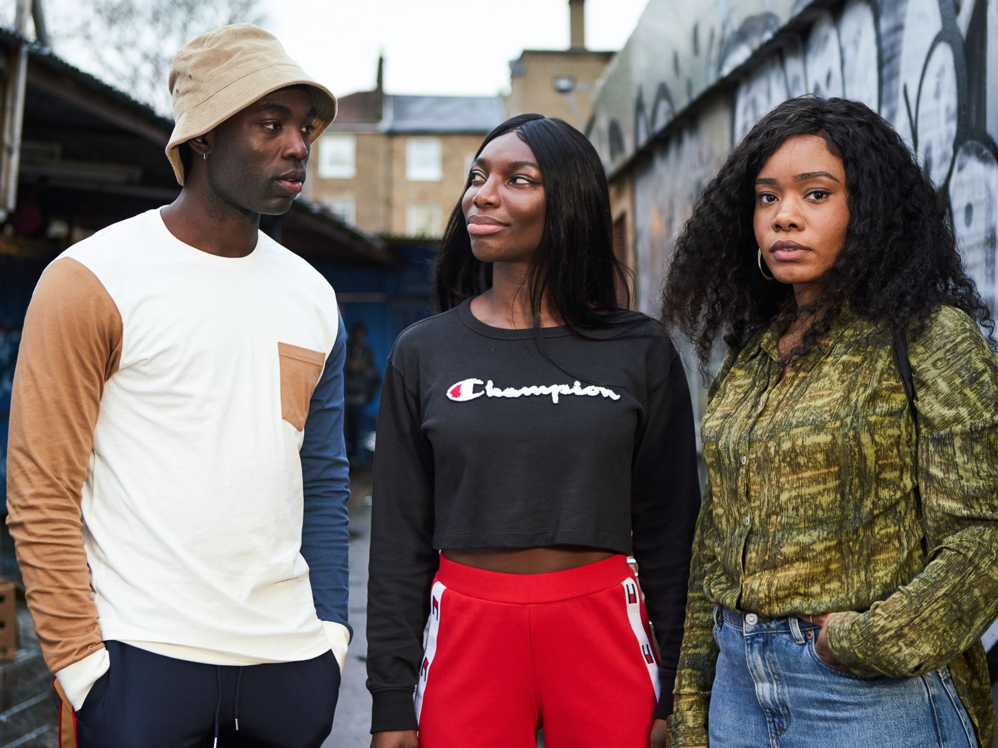 Michaela Coel and the cast of HBO's 'I May Destroy You' standing in a London alley. Wearing streetwear and bucket hat.