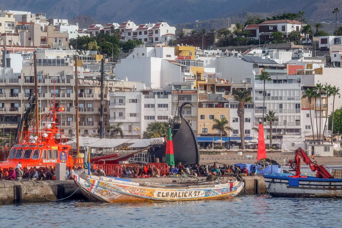 More than 150 migrants sit on the pier after arriving aboard two boats at the port of Los Cristianos, in Tenerife, on October 23, 2023. More than 1,400 African migrants have reached Spain's Canary Islands this weekend, with one vessel bringing a single-boat record of 321 people, authorities said yesterday.