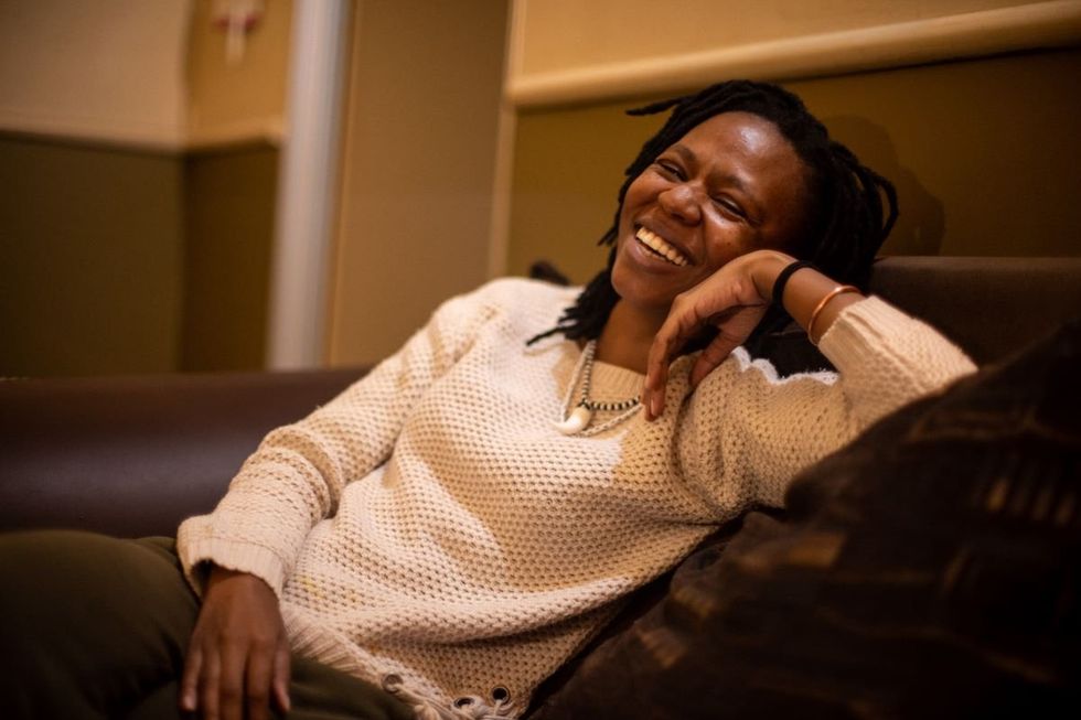 Motshewa Khaiyane looks comfortable sitting on a couch and laughing.