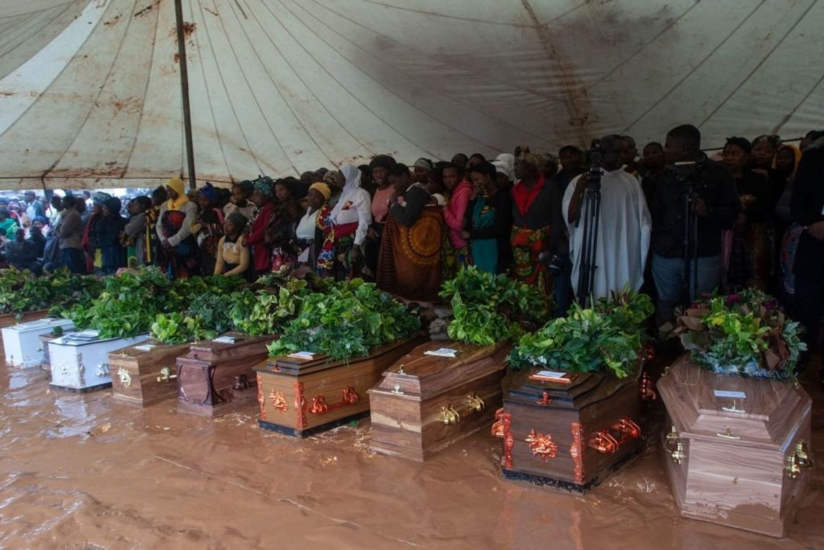 Mourners stand behind coffins of their relatives during a mass funeral for mudslide victims at Chilobwe townships Naotcha Primary school camp in Blantyre, Malawi, on March 15, 2023