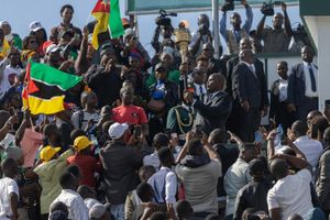Mozambican President Daniel Chapo holds the torch of freedom, surrounded by people waving the Mozambique flag in a stadium