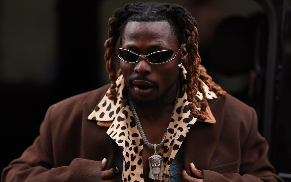 Mr. Money is seen wearing dark silver Gucci shades, brown braids, jeans trousers and a jeans jacket, a brown coat and a animal printed leotard shirt outside during the Bluemarble Menswear Spring/Summer 2024 as part of  Paris Fashion Week on June 21, 2023 in Paris, France.