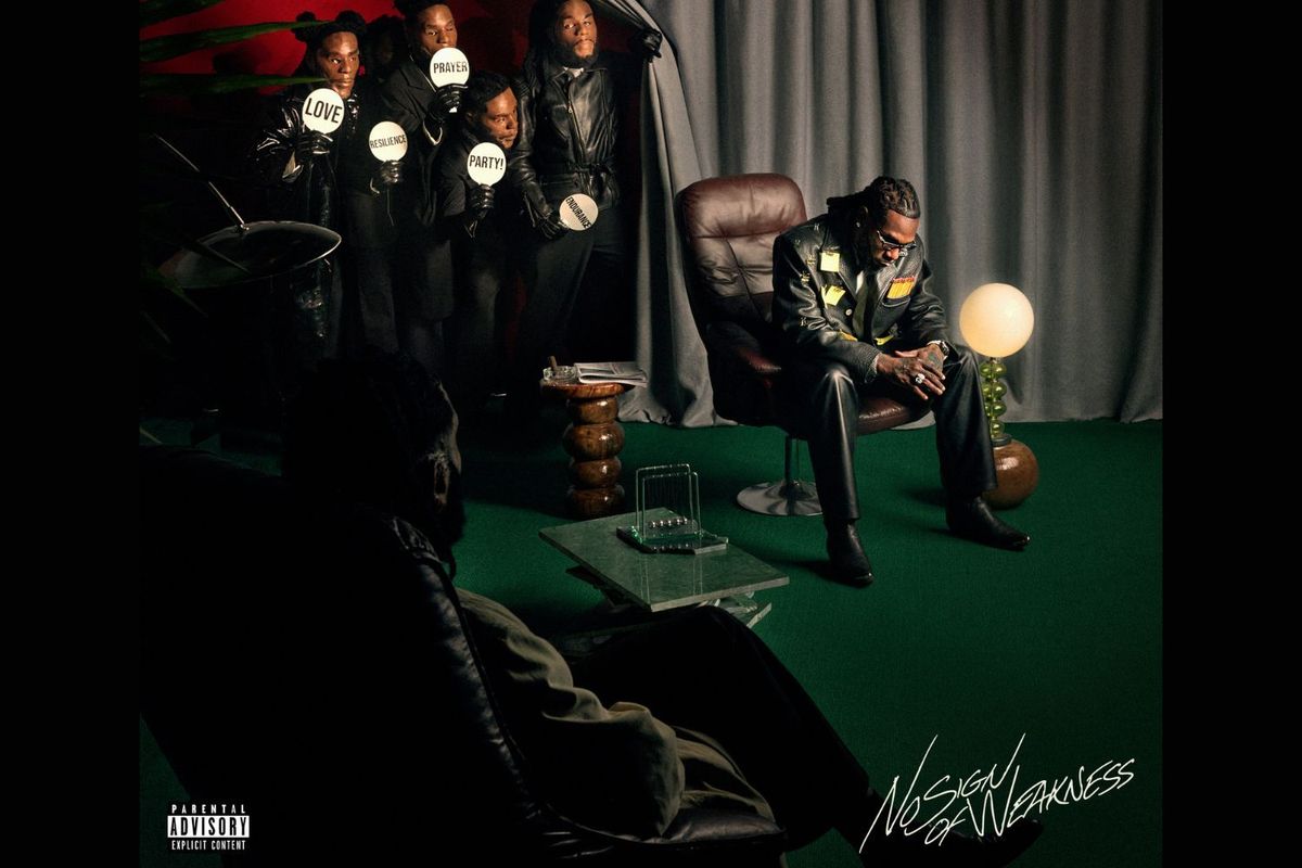 Multiple versions of Burna Boy, one sitting on a brown leather chair, while four others stand behind him, looking at him and holding up signs, and the last one sitting on the side looking at the central Burna Boy.