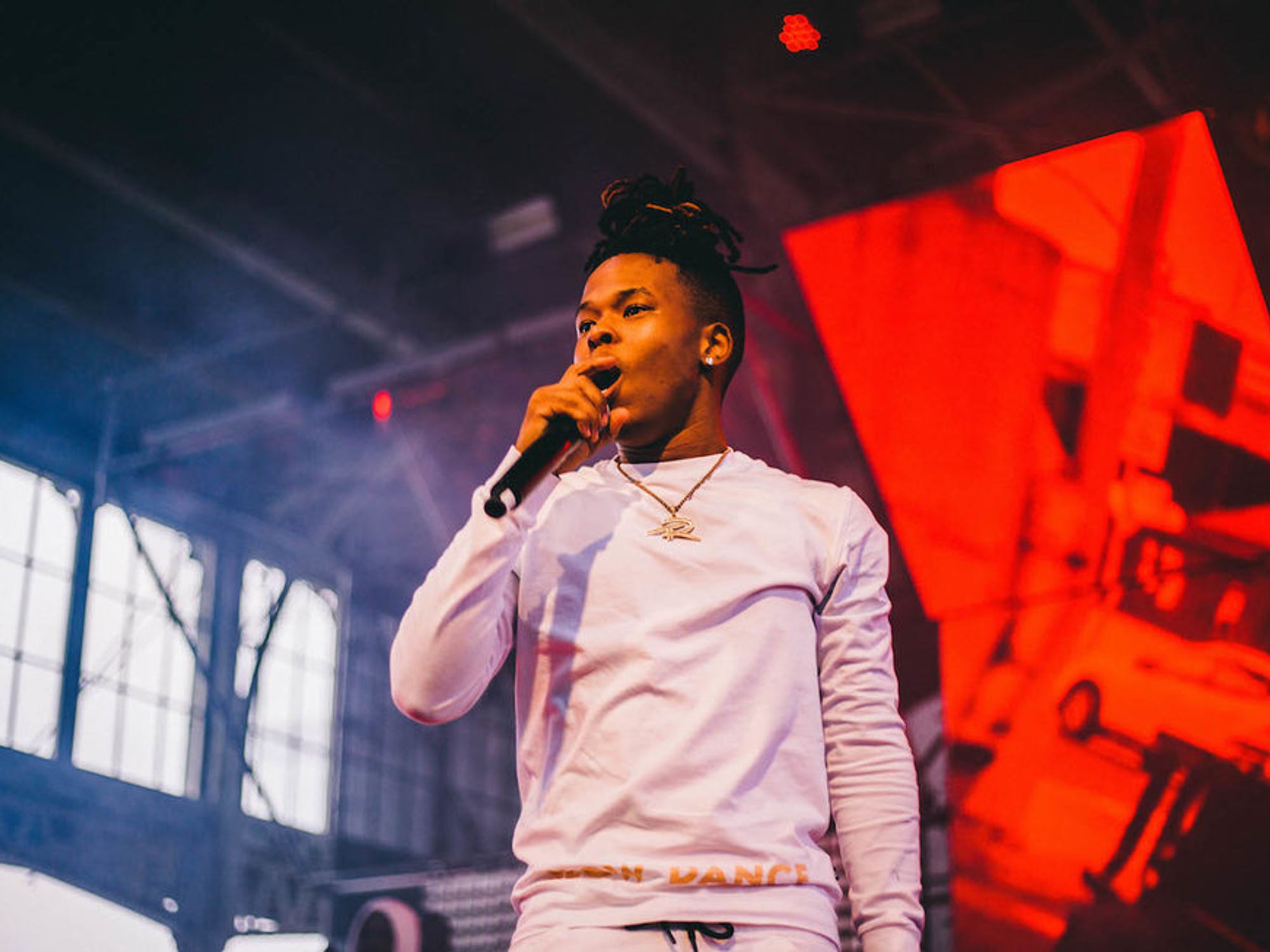 Nasty C holding a microphone and dressed in all white. 