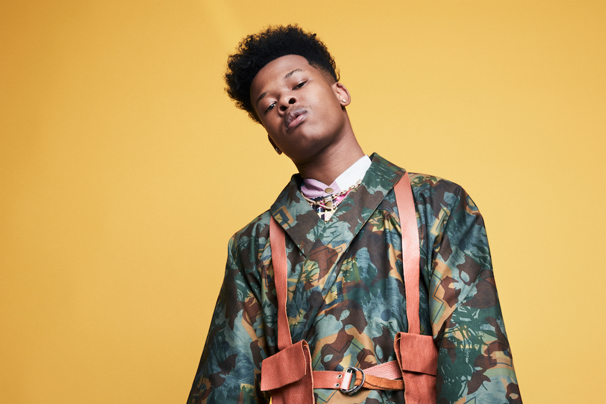 Nasty C poses in front of amber backdrop. 