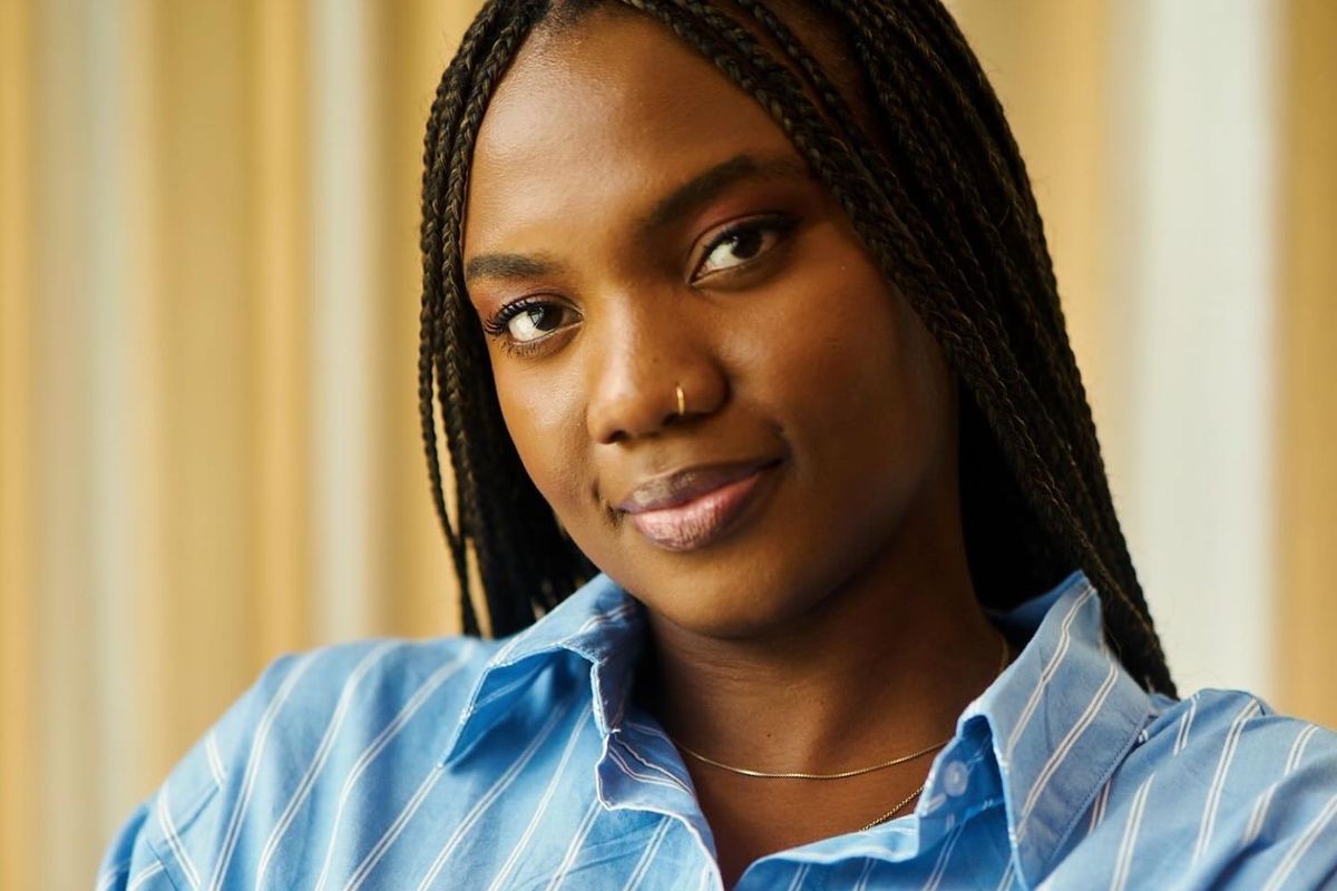 Nigerian author Esther Ifesinachi Okonkwo poses for a portrait shot in a blue shirt and long black braids.