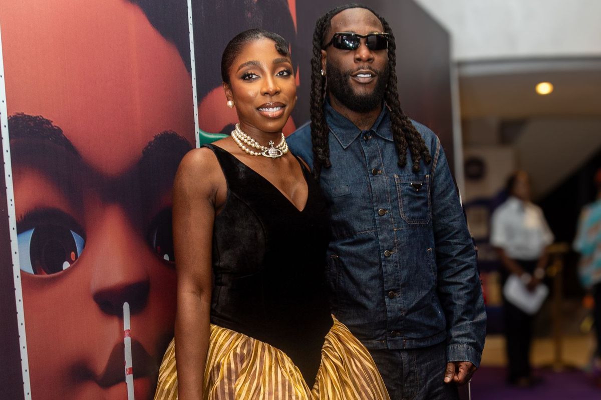 Nissi Ogulu and Burna Boy stand in front of a SOPO background and smile at the camera