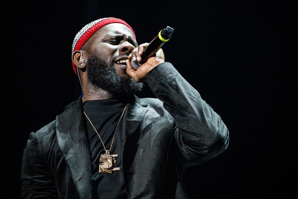 ODUMODUBLVCK performs onstage wearing a black jacket and black top, and gold jewelry.