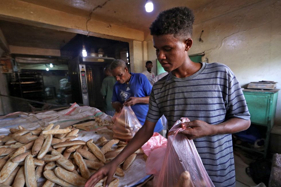 People bagging bread in pink plastic bags in a bakery