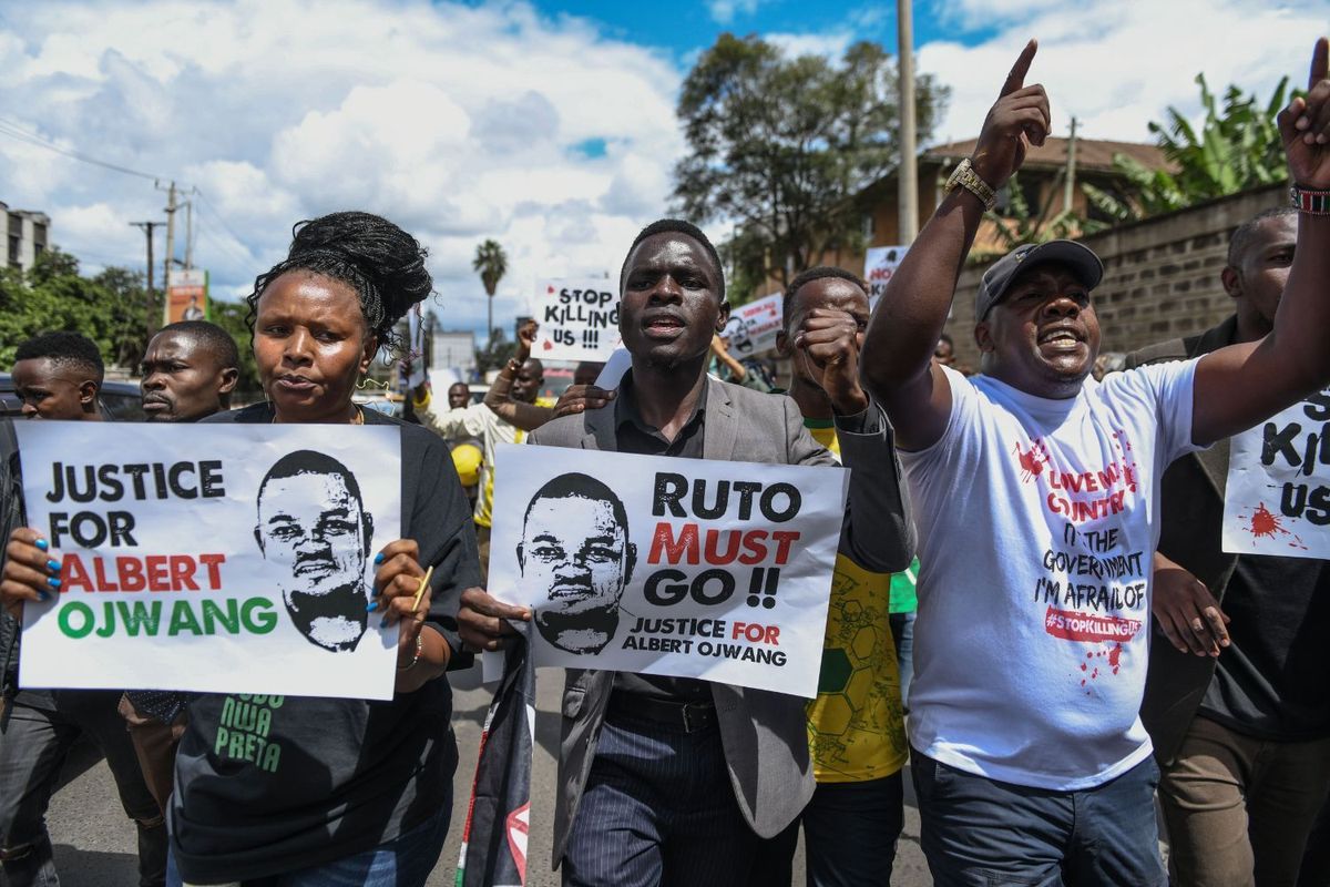 Protesters march on a Kenyan street, holding signs demanding justice for Albert Ojwang and calling for President Ruto’s resignation.