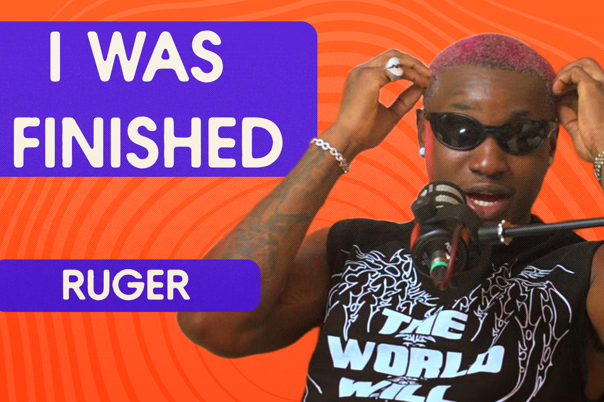 Ruger speaking into a microphone during a podcast interview, wearing sunglasses and a black sleeveless shirt with the text 'THE WORLD WILL'.