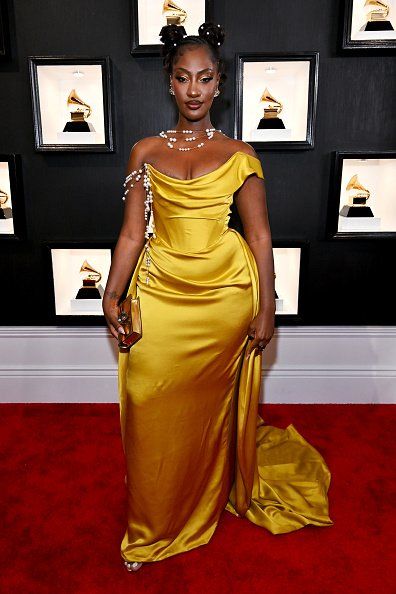 Tems on the red carpet in a gold dress. 