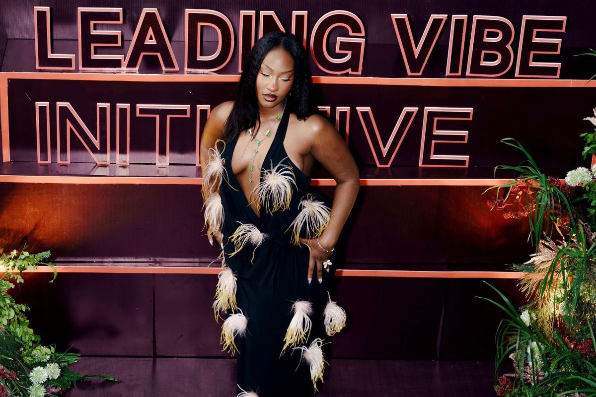 Tems poses in front of a huge sign at the dinner reception of the Leading Vibe Initiative.