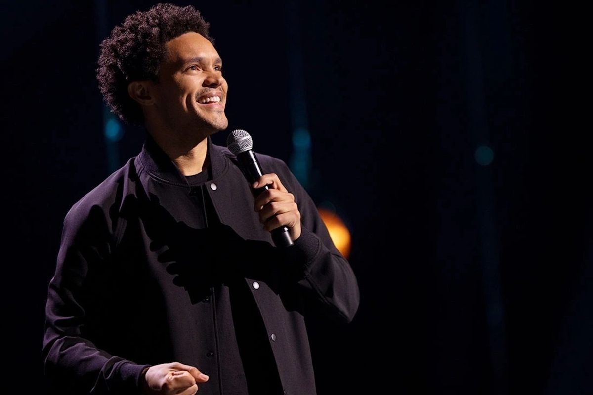 Trevor Noah in a black jacket with a microphone. 