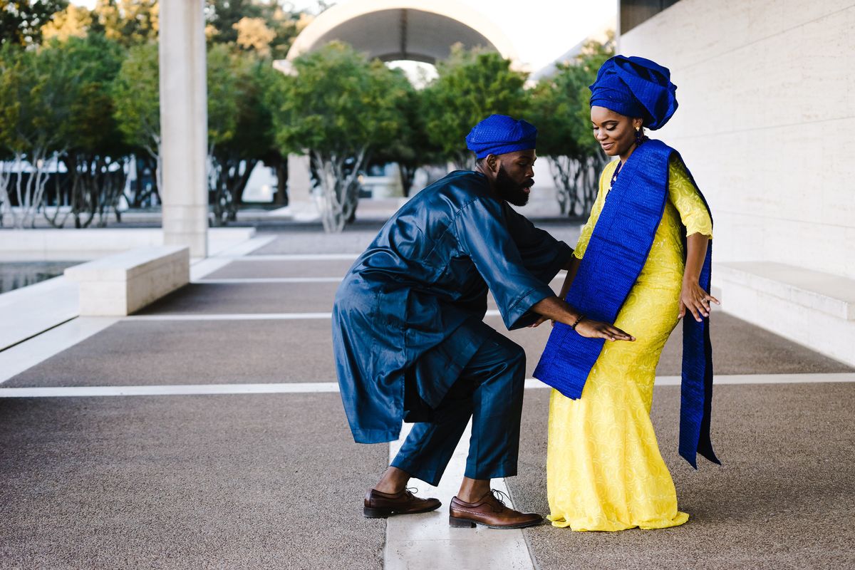Two people in traditional wedding gear dance at their African wedding.