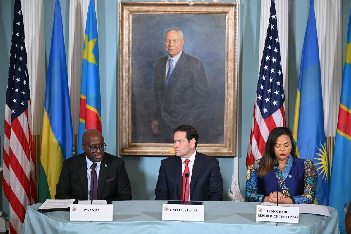 US Secretary of State Marco Rubio and Democratic Republic of the Congo Foreign Minister Thérèse Kayikwamba Wagner listen as Rwandan Foreign Minister Olivier Nduhungirehe speaks. They sit at a table in front of the three countries’ flags.
