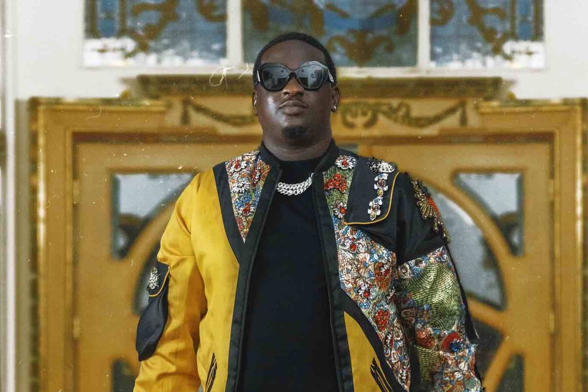 Wande coal poses standing in a luxurious jacket and sunglasses.