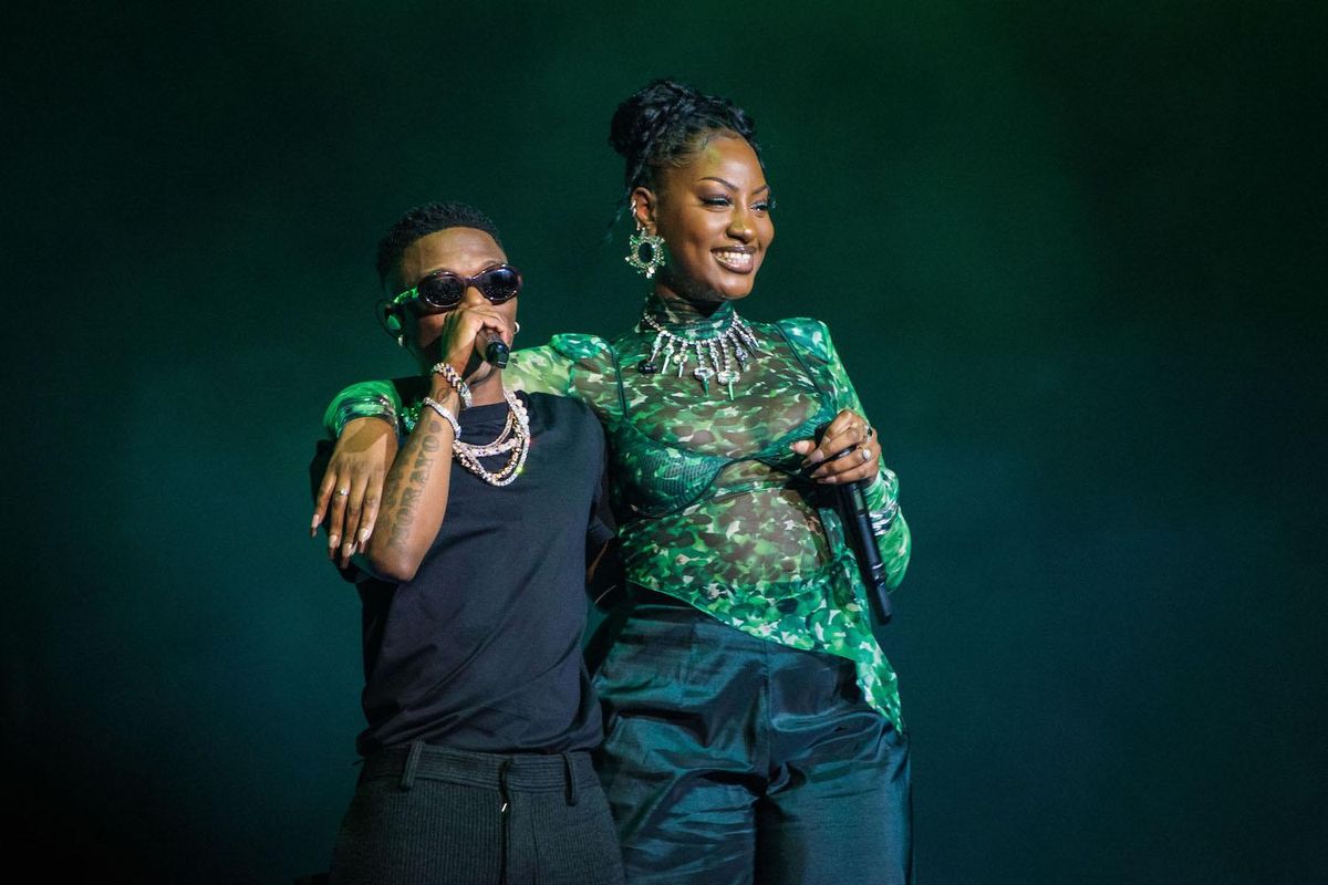 Wizkid and Tems performing together wearing green shirt and sunglasses.  