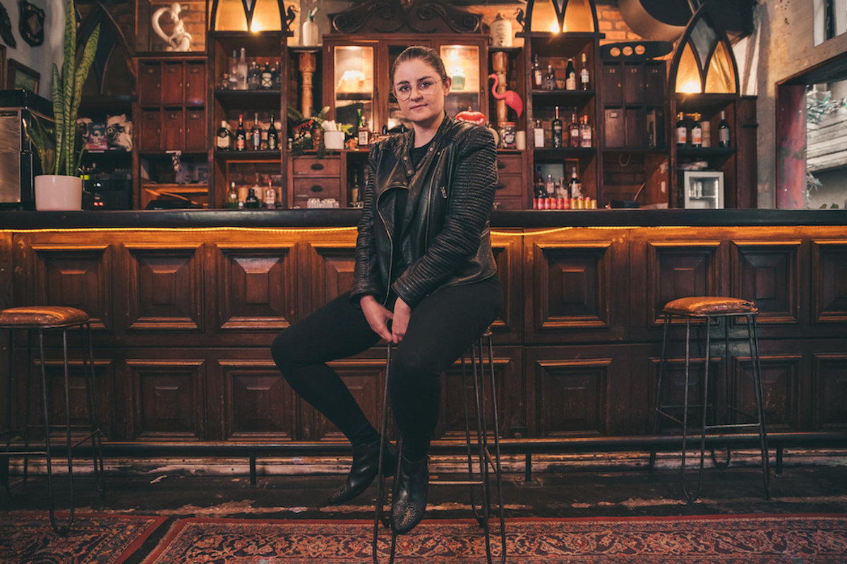 Woman wearing all black sitting on a bar stool. 