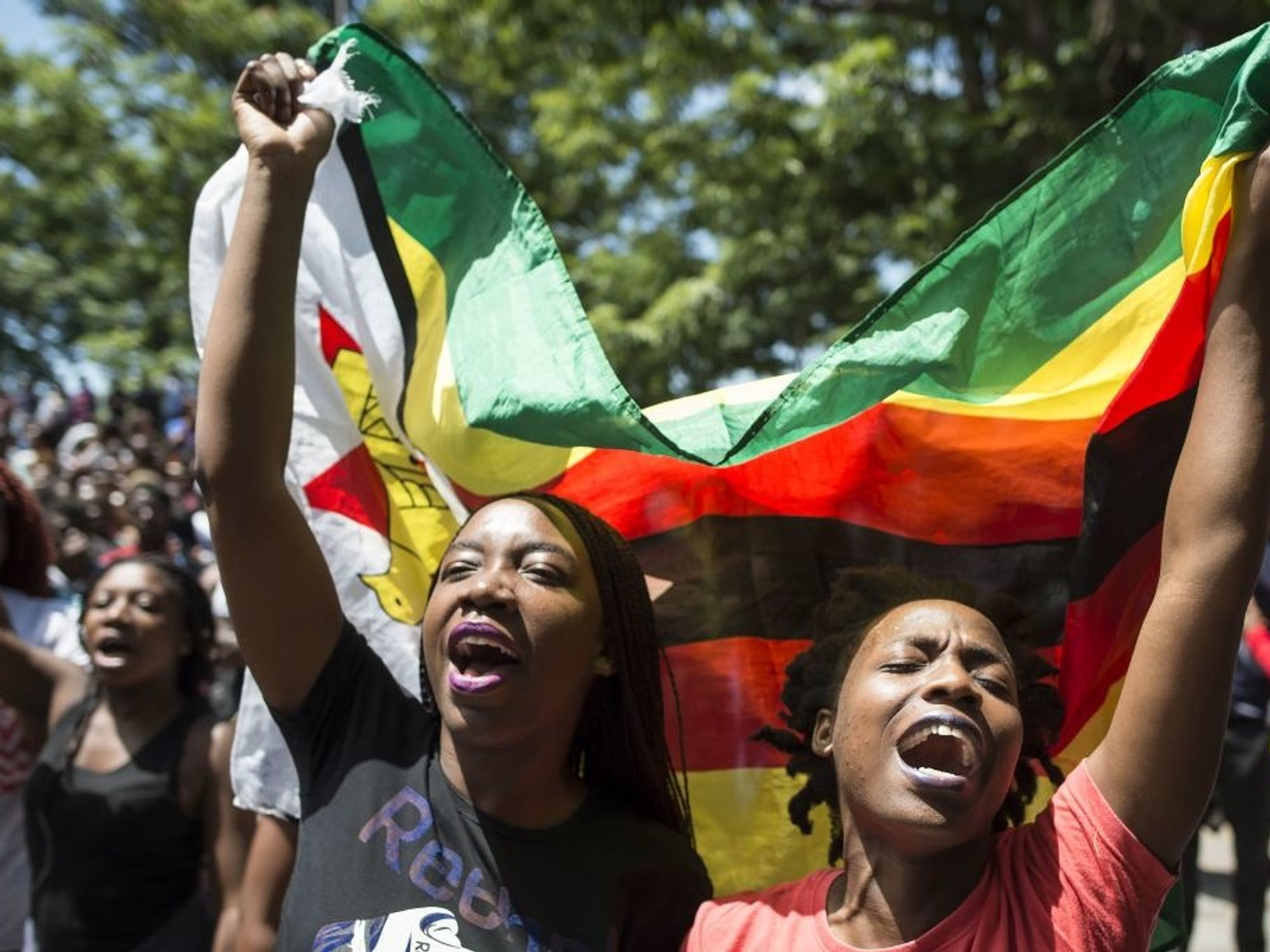 Women holding a flag of Zimbabwe take part in a demonstration of University of Zimbabwe's students, on November 20, 2017 in Harare, to demand the withdrawal of Grace Mugabe's doctorate and refused to sit their exams as pressure builds on Zimbabwe's President Robert Mugabe to resign.