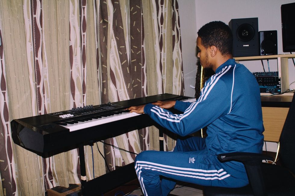 Xplosive DJ playing a keyboard in his home studio. 
