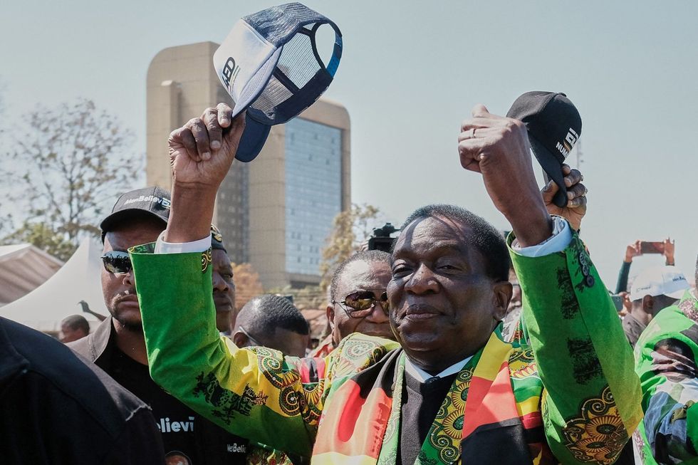 Zimbabwean President and Zanu-PF leader Emmerson Mnangagwa raises his cap in salute to the crowd gathered during a rally in Harare on August 9, 2023.