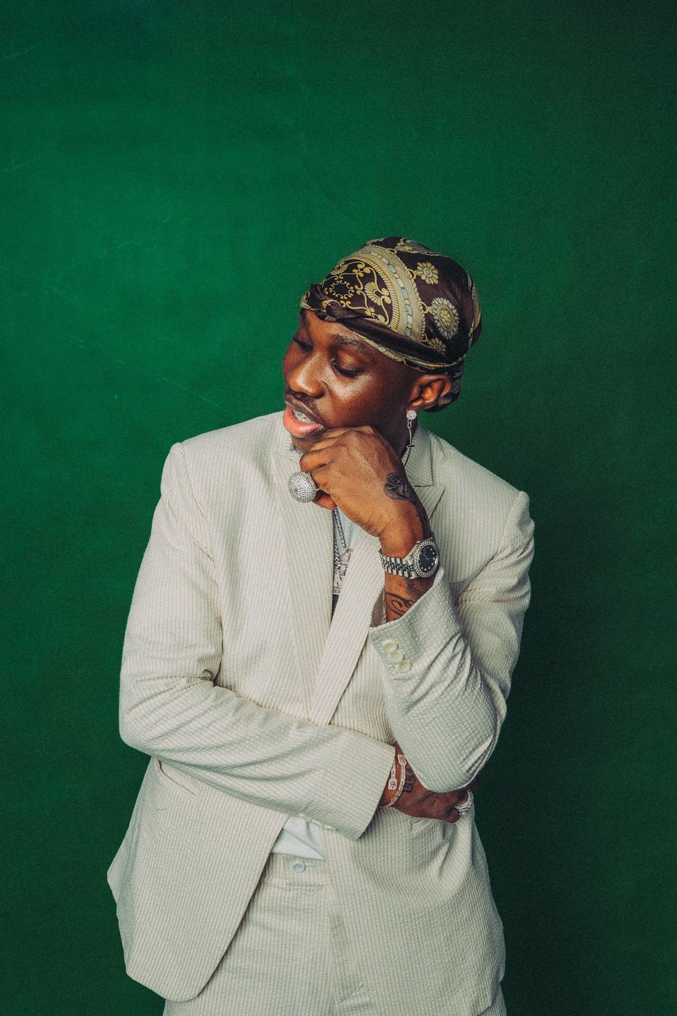 Zlatan Ibile poses for press shots in front of a green backdrop.